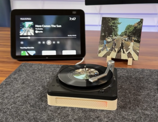 DIY Spotify Record Player

A compact turntable with a black platter and cream-colored base playing a vinyl record, accompanied by a tablet displaying Spotify's "Here Comes The Sun" track and a framed Abbey Road album cover, all arranged on a gray surface.